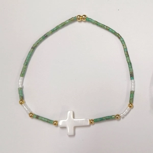 Pulsera artesanal de cuentas verdes con colgante de cruz de nácar y detalles dorados