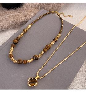 Dettaglio della collana di perle occhio di tigre e catena d'oro con ciondolo marrone