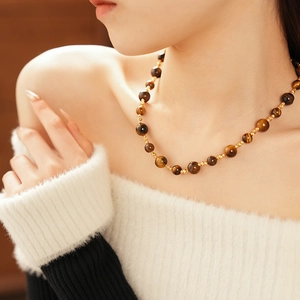 Dettaglio della collana in occhio di tigre con perle placcate oro sul collo di una modella