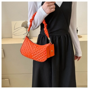 Orange quilted shoulder bag with cloud handle and small coin purse on a model