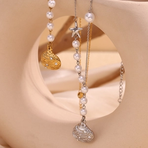 Detail of gold and silver shell pendants with small diamonds on pearl chain necklaces