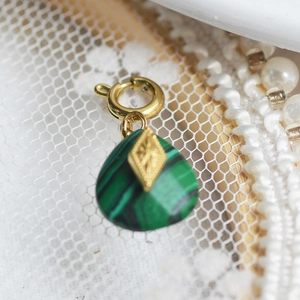Close-up of green malachite pendant with golden diamond-embossed clasp on lace