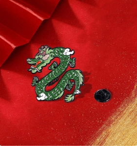 Macro shot of green enamel dragon brooch with butterfly clasp on a red textured background