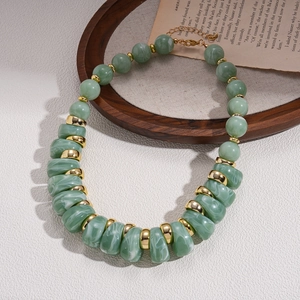 Detail of green acrylic irregular beads and gold metal rings on a vintage tray