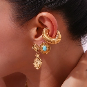 Macro view of gold-plated angel coin drop earrings and vintage turquoise stud on ear