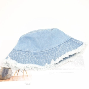 Close-up of light blue denim bucket hat with frayed edges on a fashion magazine