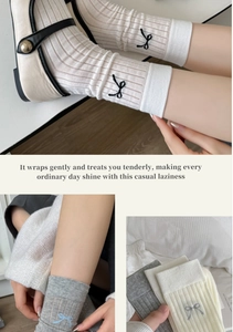 Detail of grey ribbed cotton socks featuring delicate embroidered bow and soft texture