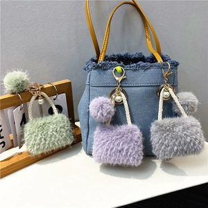 Mini plush bag keychains in mint, lavender, and grey with pearls on a denim background