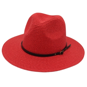 Dettaglio di un cappello Panama rosso con cinturino in pelle nera e fibbia in metallo