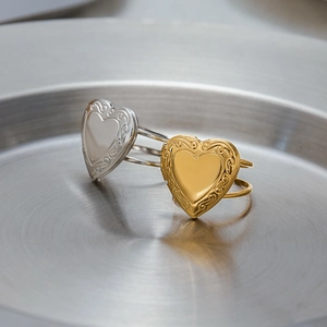 Close-up of heart-shaped stainless steel rings in gold and silver with relief textures