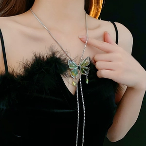 Close-up of a silver-tone butterfly tassel necklace with green and black enamel details