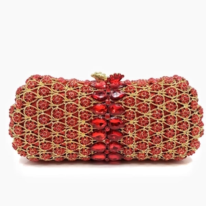 Close-up of red crystals and drop-shaped gemstones on a gold hollow evening clutch bag