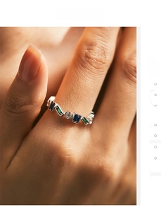 Macro view of S925 silver ring featuring alternating green, blue and clear gemstones