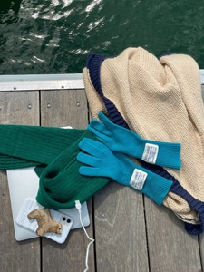 Guantes de punto azules con función táctil y etiqueta vintage sobre plataforma de madera