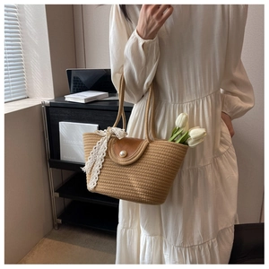 Detail of beige straw bag with leather flap, pearl button, and white lace ribbon handle