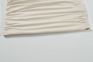 Detail of cream ruched fabric showing dense pleats and texture of the sexy deep V dress