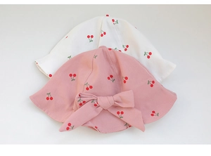 Close-up of pink and white baby sun hats with cherry print and cute bow detail