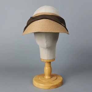 Detail of woven straw open-top sun hat with brown bow tie on a display stand