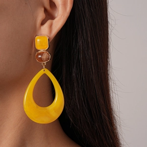 Close-up of yellow resin water drop earring with square gem and tortoise oval link