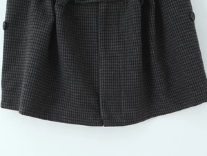 Close-up of houndstooth plaid skirt with thick wool fabric and black button details