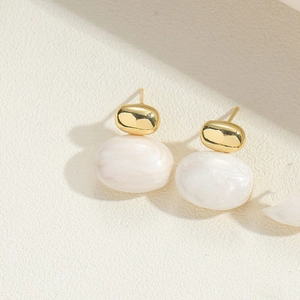 Detailed view of elegant gold-plated oval earrings with white resin shell pendants
