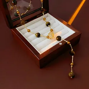 Tiger eye stone long tassel necklace with zircon charms on a vintage wooden jewelry box