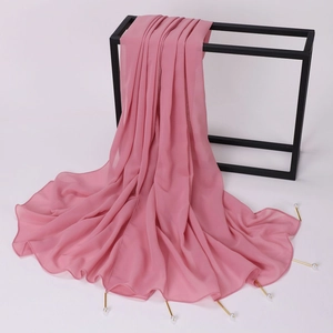 Detail of pink chiffon scarf featuring gold tube accents and white pearl beads on a rack