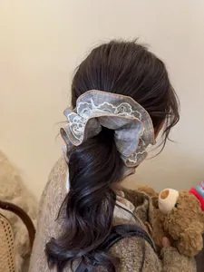 Detail of blue plaid fabric and white embroidered lace trim on a large scrunchie