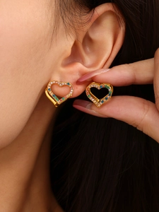 Macro shot of gold heart-shaped hoop earrings with colorful zircon inlay on model