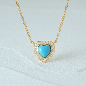 Macro shot of gold necklace featuring turquoise heart pendant with diamond halo