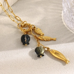 Detail of 18K gold paperclip necklace featuring gold and black fish pendants