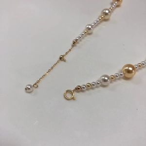 Detailed macro view of the gold lobster clasp and adjustable chain on the pearl necklace
