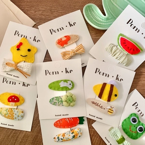 Handmade felt animal hair clips with colorful cartoon shapes on wooden background