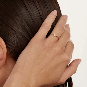 Detail of a gold cocktail ring with triple gems worn elegantly by a model