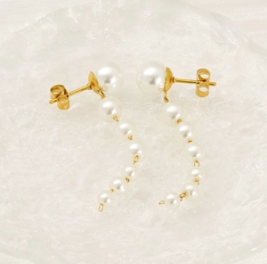 Macro detail of long pearl tassel earrings with golden chain and large stud pearl