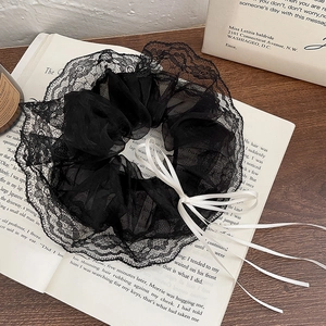 Detail of black lace scrunchie with white satin ribbons on vintage book background