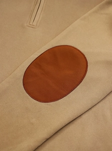 Detailed close-up of khaki knit sweatshirt fabric with brown oval elbow patch