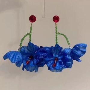 Détail de boucles d'oreilles florales avec perles rouges, tiges vertes et fleurs en tissu