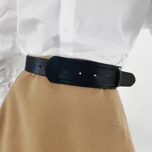 Close-up of wide black leather belt with square buckle on white shirt and camel skirt