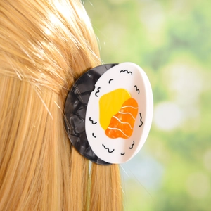 Close-up of a creative sushi-shaped acetate hair claw clip worn on blonde hair