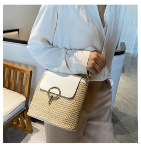 Detail of woven straw bucket bag featuring cream leather flap and gold ring buckle