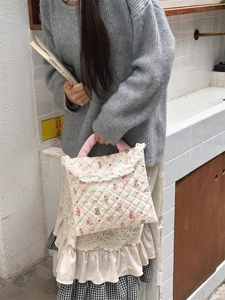 Detail of quilted laptop bag with pink floral patterns and white lace trim edge