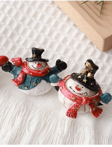Detailed view of two resin snowman figurines wearing red scarves and hats on white knit