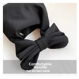 Detailed close-up of a black bucket bag featuring a large bow and a silver metal zipper