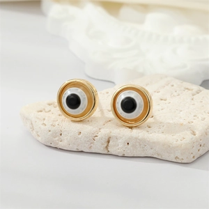 Vintage gold evil eye stud earrings with resin glitter on white stone pedestal