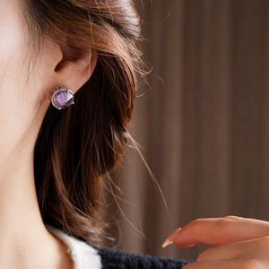 Close-up of 18k gold plated silver earring with purple zircon stone on a model