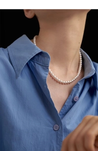 Detail of high-quality pearl necklace with subtle pink luster on a blue shirt