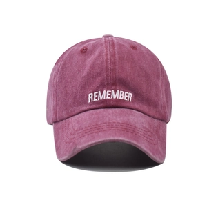 Detail of REMEMBER embroidery on a vintage washed pink cotton baseball cap