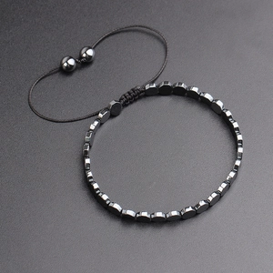 Detail of adjustable woven hematite bracelet with magnetic geometric beads on black background