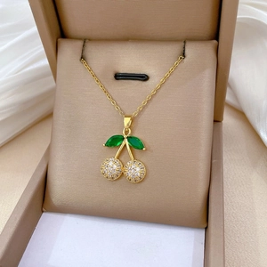 Macro shot of cherry pendant with green gemstones and pavé zircon in jewelry box